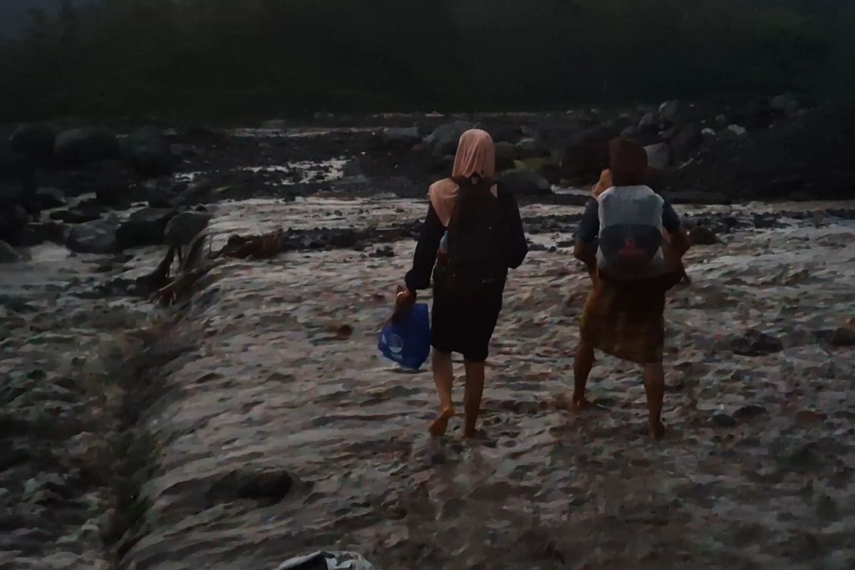Siswa di Lumajang harus menunggu banjir lahar Semeru surut sebelum bisa menyeberangi sungai. 
