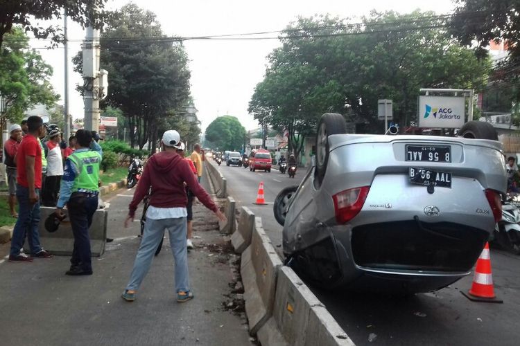 Sebuah sedan terbalik setelah menabrak separator busway di Jalan Marga Satwa, Jatipadang, depan SMKN 57 Jakarta, Minggu (12/11/2017) pagi.