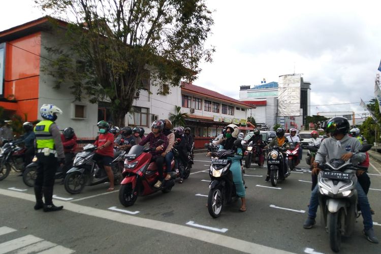 Petugas Satlantas Polresta Samarinda sedang mengatur para pengendara yang berhenti di lampu lalulintas menunggu pergantian lampu merah di simpang Kantor Pos Jalan Awang Long, Samarinda, Kaltim, Rabu (15/7/2020). 