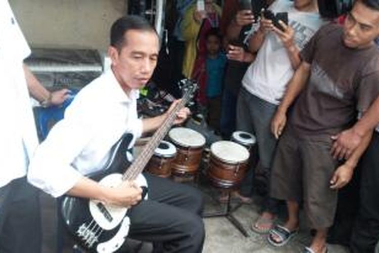 Presiden terpilih Joko Widodo mencoba bas di pasar barang bekas Notoharjo, Solo, Jawa Tengah, Sabtu (26/7/2014) siang.