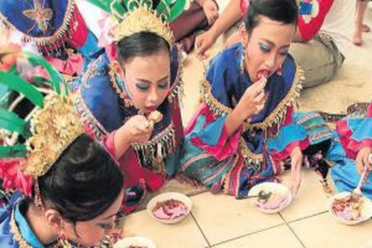 Para penari tari Lenggang Nyai menikmati bubur ase sebelum mengiringi sebuah pesta pernikahan di kawasan Senayan, Jakarta, Mei 2013. Bubur ase, makanan khas Betawi yang sudah langka, merupakan campuran dari bubur ayam, asinan sawi, dan semur. 