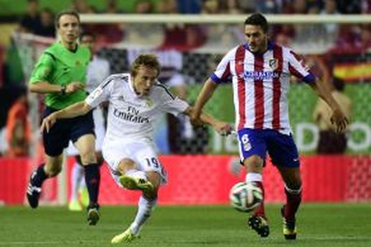 Gelandang Real Madrid Luka Modric (tengah) melepaskan tendangan meski mendapat kawalan gelandang Atletico Madrid, Koke, pada leg kedua Piala Super Spanyol di Vicente Calderon, Jumat (22/8/2014).