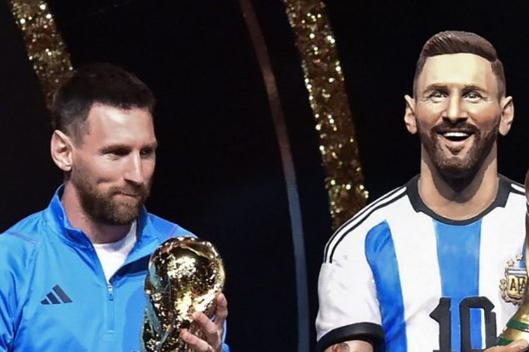 Lionel Messi berdiri di samping patung dirinya dalam agenda penghormatan dari Conmebol usai Argentina juara Piala Dunia 2022. Acara ini bergulir di markas Conmebol, Luque, Paraguay Senin (27/3/2023). (Foto oleh NORBERTO DUARTE / AFP)