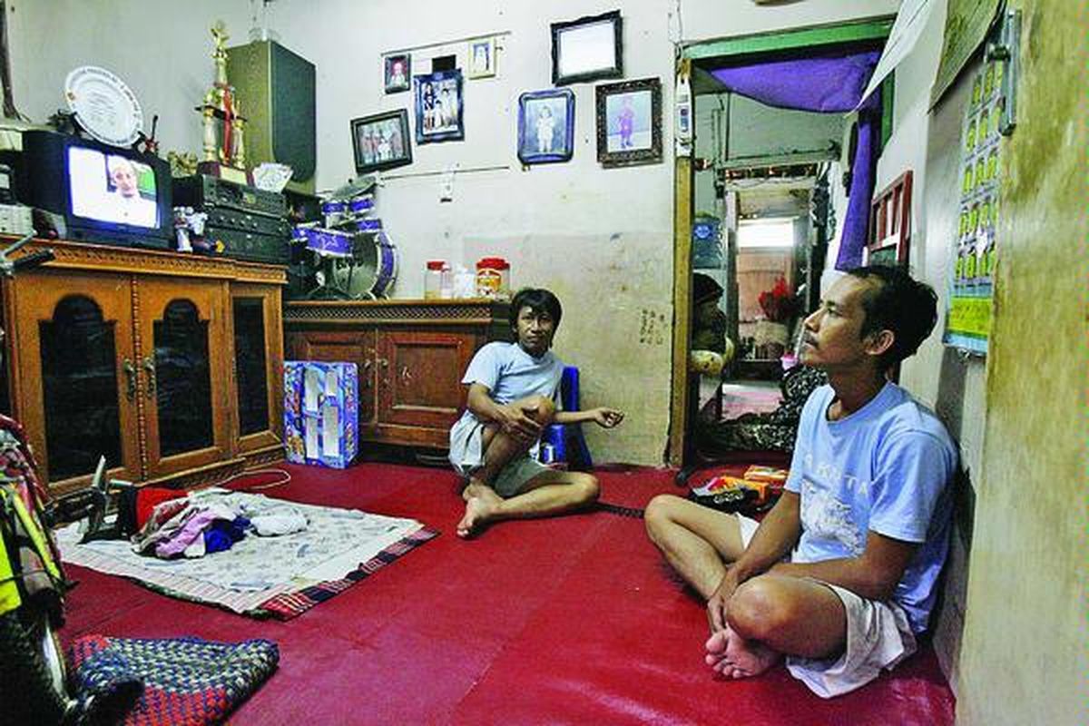 Sudalyana (kanan), buruh yang dirumahkan oleh PT Jakarta Kyoei Steel dan Slamet, seorang buruh korban pemutusan hubungan kerja (PHK) dari PT Tri Manunggal Nusa Perkasa menonton televisi di rumah kontrakannya di RT 002 RW 10 Pulau Jahe, Kelurahan Jatinegara, Kecamatan Cakung, Jakarta Timur, Senin (24/11). Keduanya dirumahkan dan dikenai PHK sejak awal Oktober 2008.  