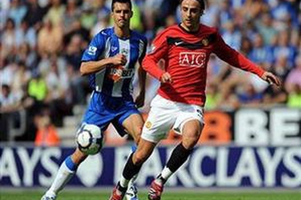 Striker Manchester United, Dimitar Berbatov, dikawal defender Wigan, Paul Scharner. Sampai babak pertama usai, MU masih ditahan Wigan 0-0.