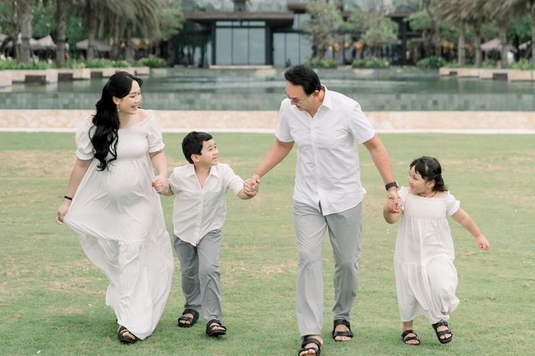Puput Nastiti Devi tampil anggun dengan long dress putih, makeup natural, dan rambut wavy saat foto kehamilan anak ketiga bersama keluarga.