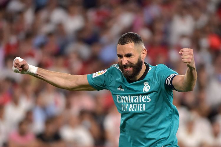 Penyerang Real Madrid Karim Benzema berselebrasi usai mencetak gol ke gawang Sevilla pada laga pekan ke-32 Liga Spanyol 2021-2022 di Stadion Ramon Sanchez Pizjuan, Senin (18/4/2022) dini hari WIB. Terkini, Benzema siap melakoni laga bertajuk El Clasico pada akhir pekan ini. Laga Real Madrid vs Barcelona dijadwalkan berlangsung di Stadion Santiago Bernabeu, pada Minggu (16/10/2022) malam WIB.