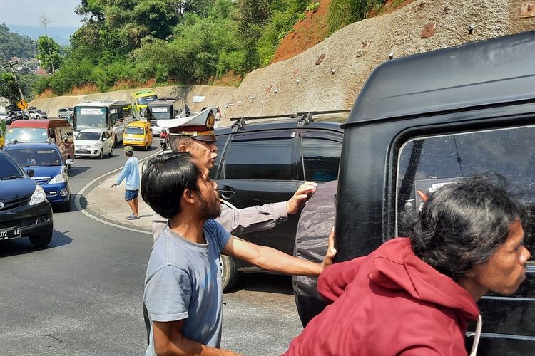 Salah seorang mobil pemudik mogok akibat tak kuat menanjak dan mendapatkan bantuan warga serta petugas Kepolisian di Tanjakan Gentong, Kabupaten Tasikmalaya, Jawa Barat, Jumat (6/5/2022).