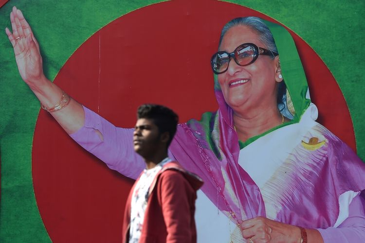 Pria Bangladesh berjalan melewati gambar Perdana Menteri Sheikh Hasina di Dhaka.