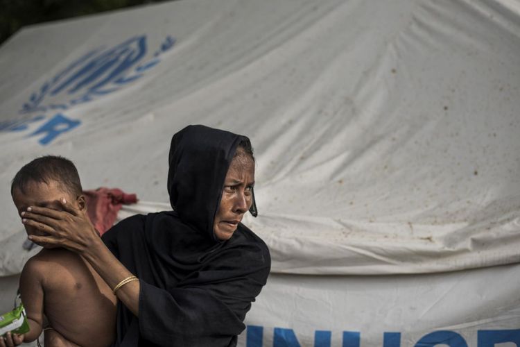 Seorang pengungsi Rohingya menahan bayinya di pusat pendaftaran setelah dia melintasi perbatasan dari Myanmar, di Teknaf, Bangladesh pada 2 Oktober 2017. Myanmar telah mengusulkan untuk membawa kembali ratusan ribu orang Rohingya yang telah melarikan diri ke Bangladesh dalam beberapa pekan terakhir.