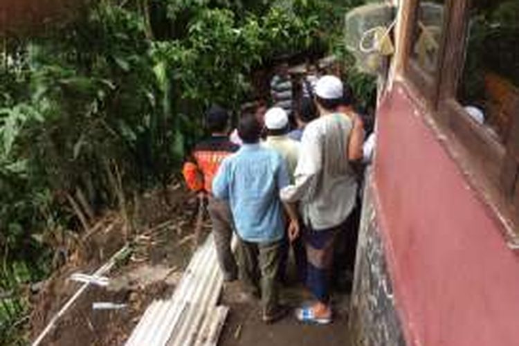 Sejumlah warga Tretes Prigen dan petugas BPBD Pasuruan berusaha menutup bagian atas tanah yang tersisa dengan asbes usai longsor melanda di kawasan tersebut. 