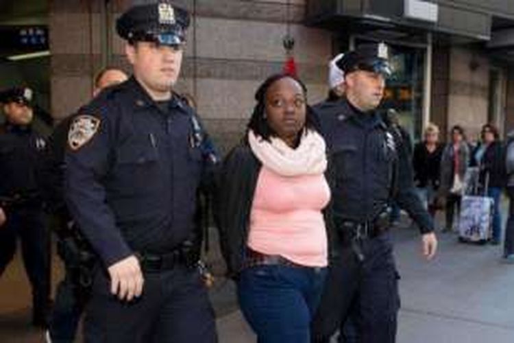 Dua personel kepolisian New York menggiring seorang perempuan yang disangka mendorong seorang perempuan lain ke jalur kereta bawah tanah.