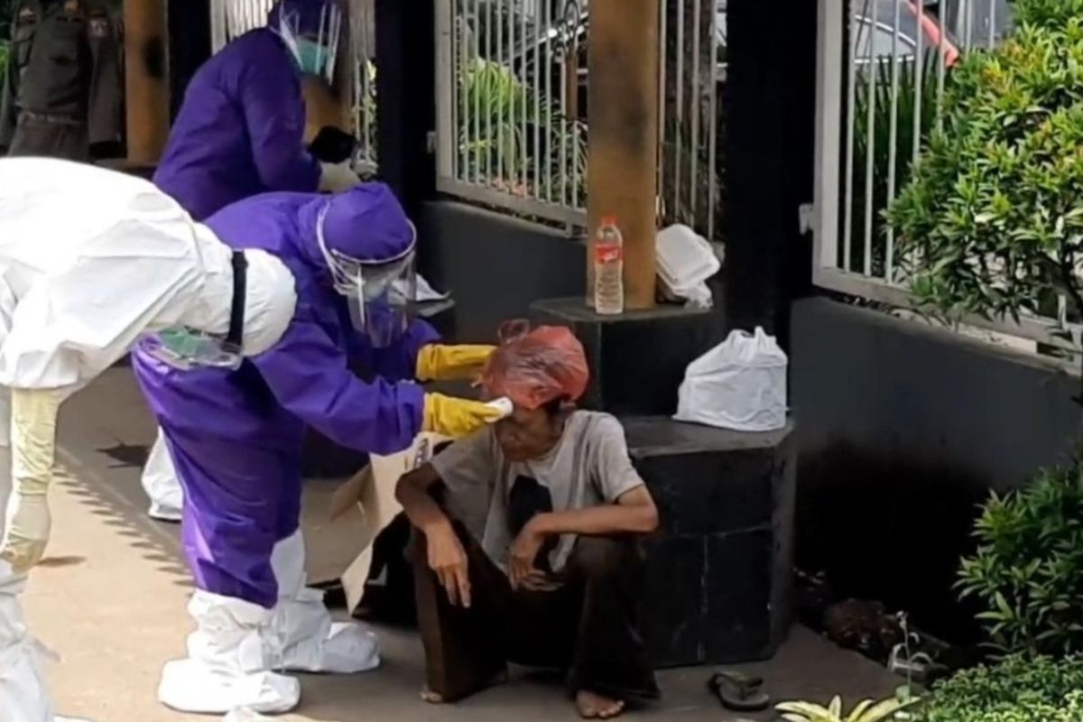 Seorang kakek jatuh pingsan di pinggir Jalan Bekasi Timur Raya, Jatinegara, Jakarta Timur, dan dievakuasi petugas medis mengenakan APD, Selasa (28/4/2020).