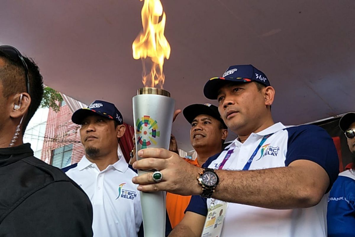 Wakil Wali Kota Jakarta Selatan Arifin memegang obor Asian Games saat prosesi torch relay atau pawai obor di Jalan Raya Rawa Bambu, Jakarta Selatan, Rabu (15/8/2018).