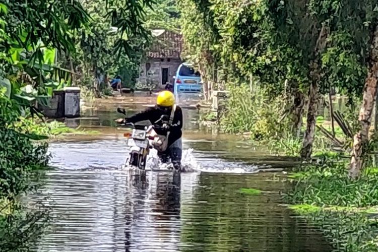 Pengendara sepeda motor mendorong kendaraanya yang macet karena terkena banjir, Jumat (24/5/2024)
