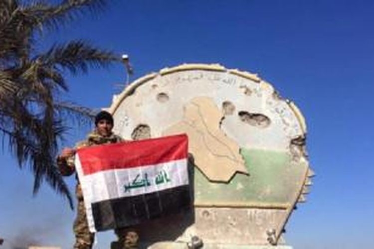 Seorang tentara Irak memegang bendera nasional di atas kompleks pemerintah di Ramadi tengah, Irak, 28 Desember 2015. 