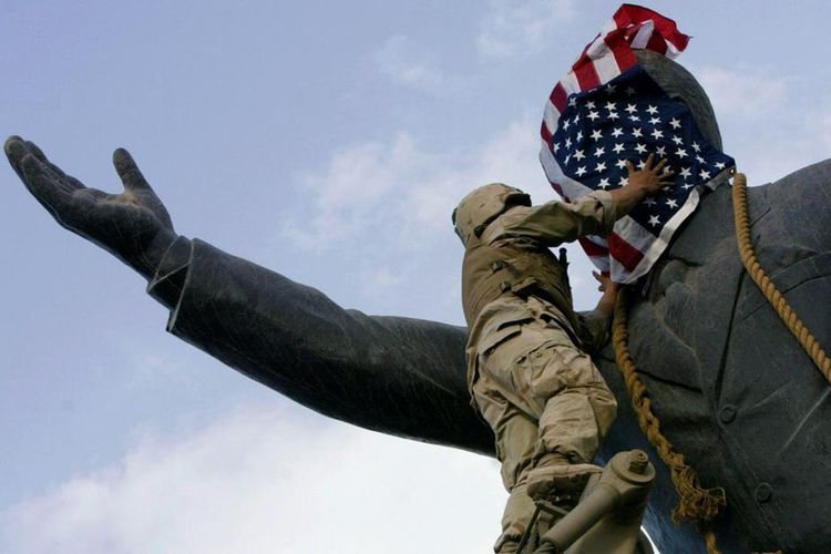 Serdadu AS menutupi patung Saddam Husein dengan bendera.