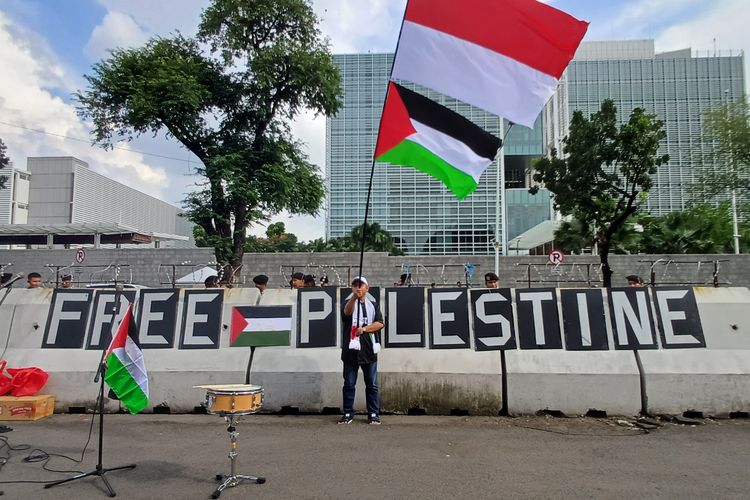 Seorang pendemo mengibarkan bendera Palestina di depan Kantor Kedutaan Besar Amerika Serikat, Jumat (19/4/2024).