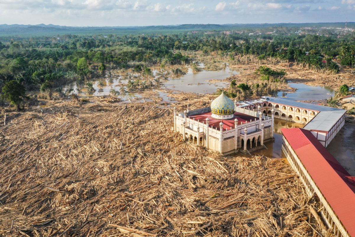 Foto udara menampilkan tumpukan kayu-kayu memenuhi area Pondok Pesantren Darul Mukhlishin pascabanjir bandang di  Desa Tanjung Karang, Karang Baru, Kabupaten Aceh Tamiang, Aceh, Jumat (5/12/2025). Usai sepekan setelah bencana banjir bandang, akses menuju Desa Tanjung Karang masih terhambat akibat banyaknya tumpukan pohon dan lumpur tebal dari Sungai Tamiang sehingga bantuan sulit masuk ke wilayah tersebut. 