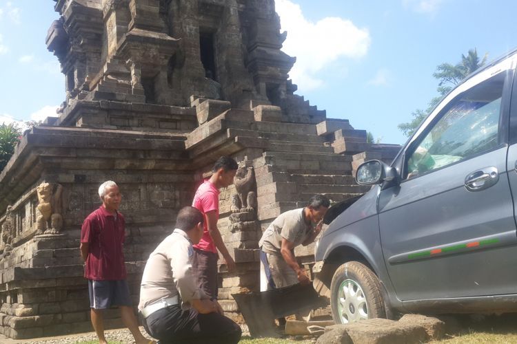 Petugas dibantu warga saat berusaha mengevakuasi mobil yang menabrak Candi Kidal, Kabupaten Malang, Selasa (25/7/2017)