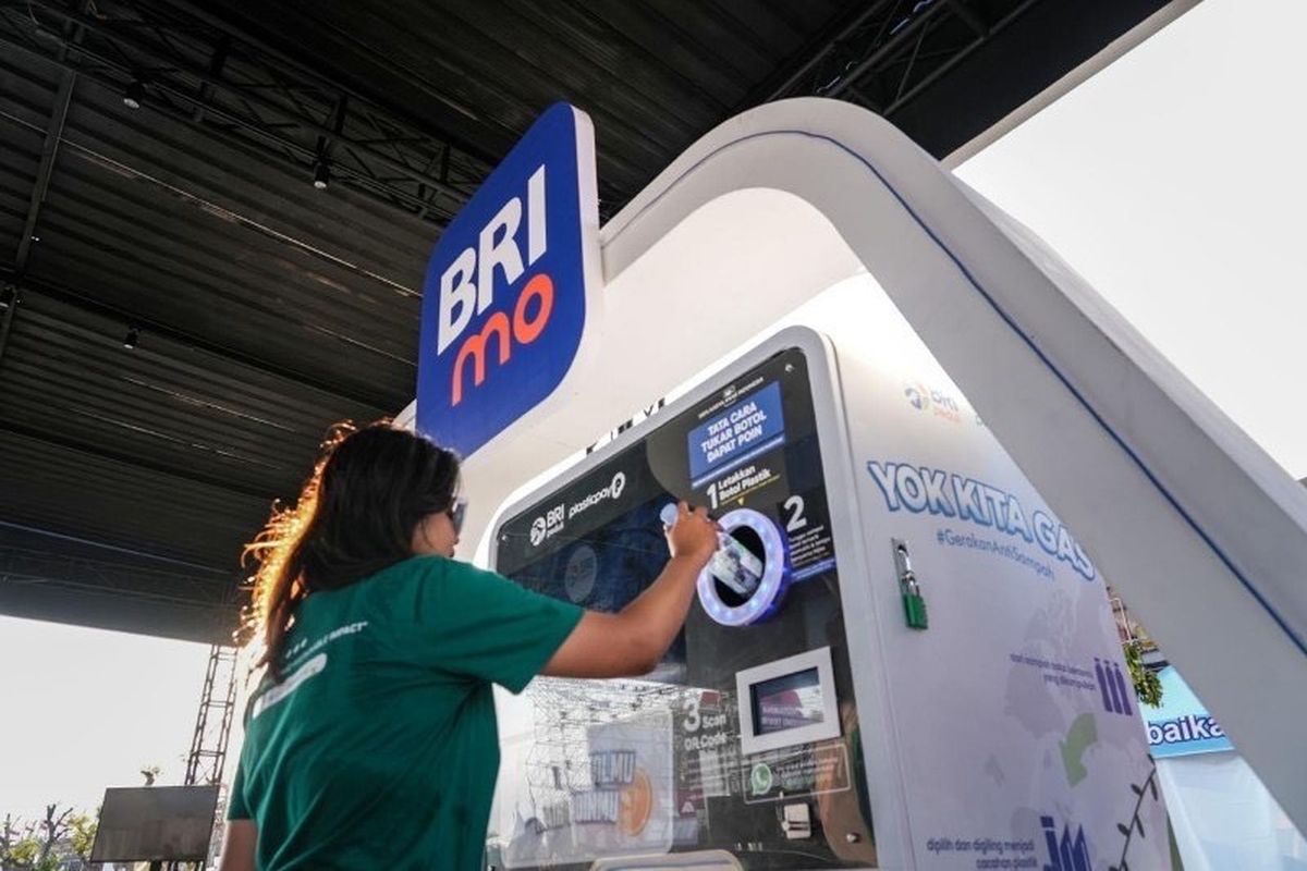 Pekerja BRI sedang menyalurkan sampah botol plastik melalui mesin Reverse Vending Machine (RVM)