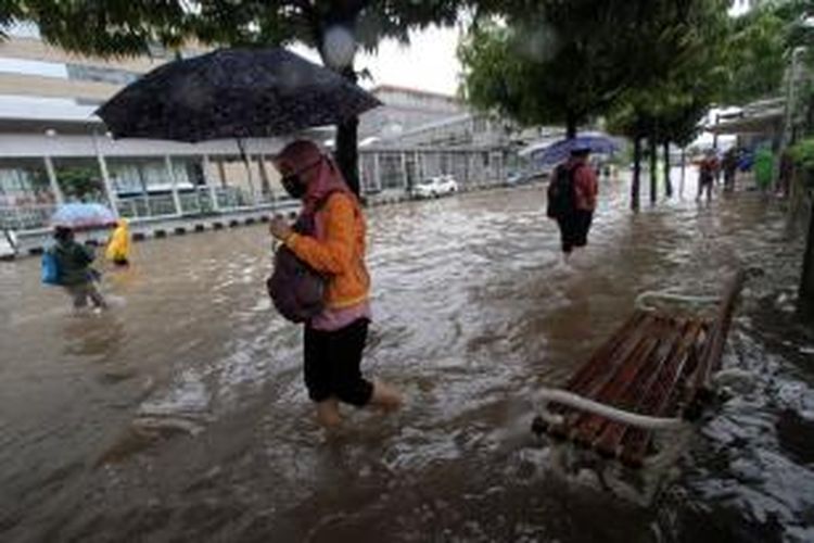 Warga melintasi trotoar yang terendam banjir di Jalan MH Thamrin, Jakarta Pusat, Senin (9/5/2015). Curah hujan yang tinggi mengakibatkan sejumlah tempat di ibu kota terendam banjir.