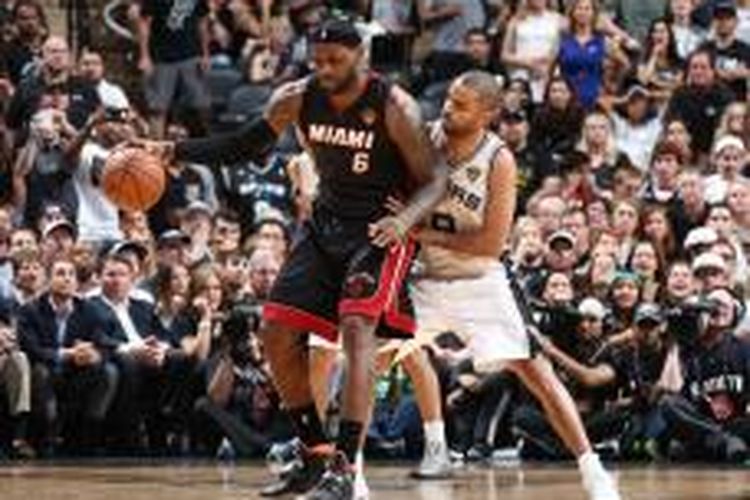 Pebasket Miami Heat, LeBron James, mencoba melewati hadangan pemain San Antonio Spurs, Tony Parker, pada laga kedua final NBA 2014 di AT&T Center, Minggu (8/6/2014). Heat menang 98-96.