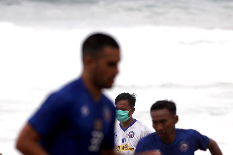 Terapis Arema FC David Setiawan tetap menggunakan masker saat memantau tim latihan selama masa pandemi virus corona.