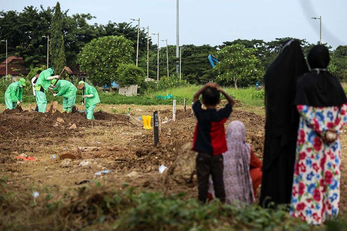 Keluarga pasien melihat dari jauh saat petugas pemakaman menguburkan jenazah pasien suspek virus corona atau Covid-19 di TPU Tegal Alur, Jakarta Barat, Kamis (26/3/2020). Pemprov DKI Jakarta telah menyiapkan dua tempat pemakaman umum (TPU) untuk memakamkan pasien terjangkit virus corona (Covid-19) yang meninggal dunia, yakni di TPU Tegal Alur di Jakarta Barat dan TPU Pondok Ranggon di Jakarta Timur. Jenazah yang dapat dimakamkan di sana, yakni yang berstatus pasien dalam pengawasan (PDP) dan berstatus positif terjangkit virus corona.