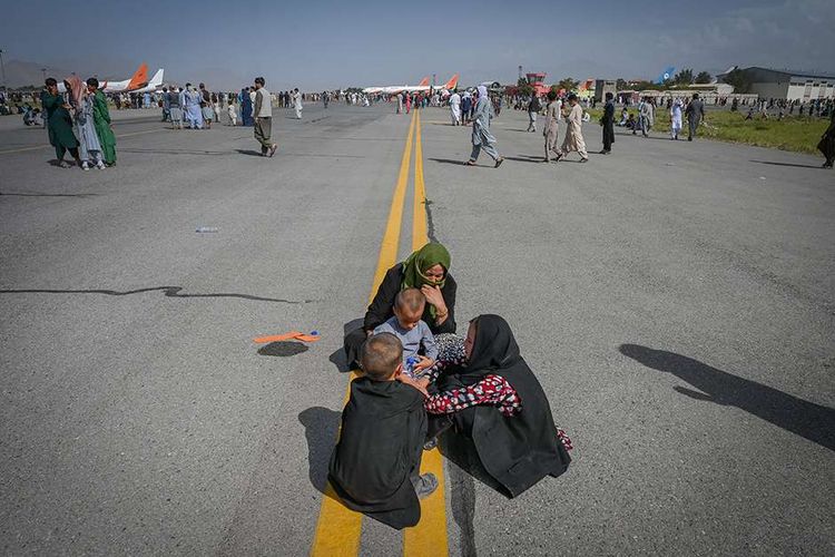 Orang-orang menunggu untuk dapat diberangkatkan dengan pesawat saat mereka berebut untuk melarikan diri ke luar negeri, di Bandara Kabul, Afghanistan, Senin (16/8/2021). Bandara Kabul dilanda kekacauan ketika ribuan orang mencoba melarikan diri dari Taliban yang dilaporkan segera menguasai penuh Afghanistan.