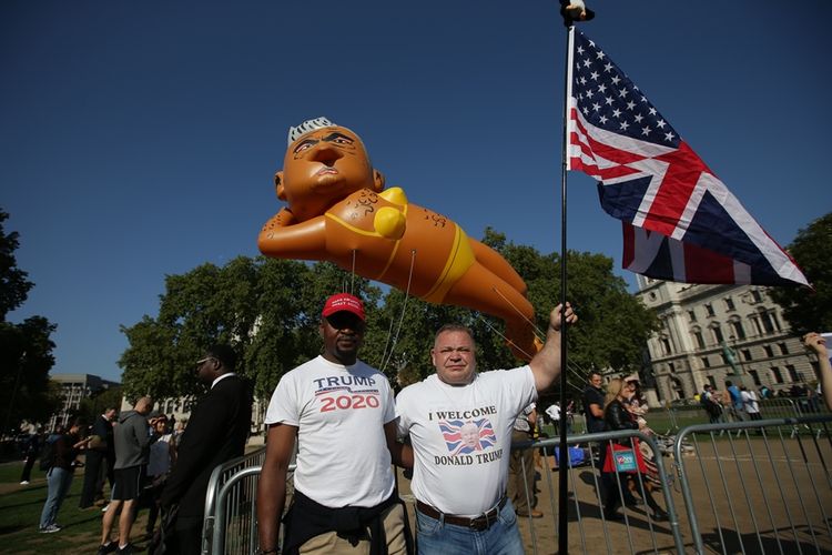 Dua warga pendukung Presiden AS Donald Trump berfoto dengan latar belakang balon raksasa karikatur Wali Kota London Sadiq Khan di Alun-alun Parlemen, Westminster, Sabtu (1/9/2018).
