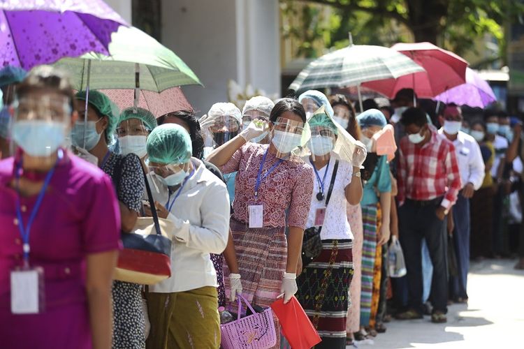 Para pemilih yang mengenakan masker pelindung wajah memberikan suara mereka di TPS dekat pagoda Shwedagon Minggu, 8 November 2020, di Yangon, Myanmar. 