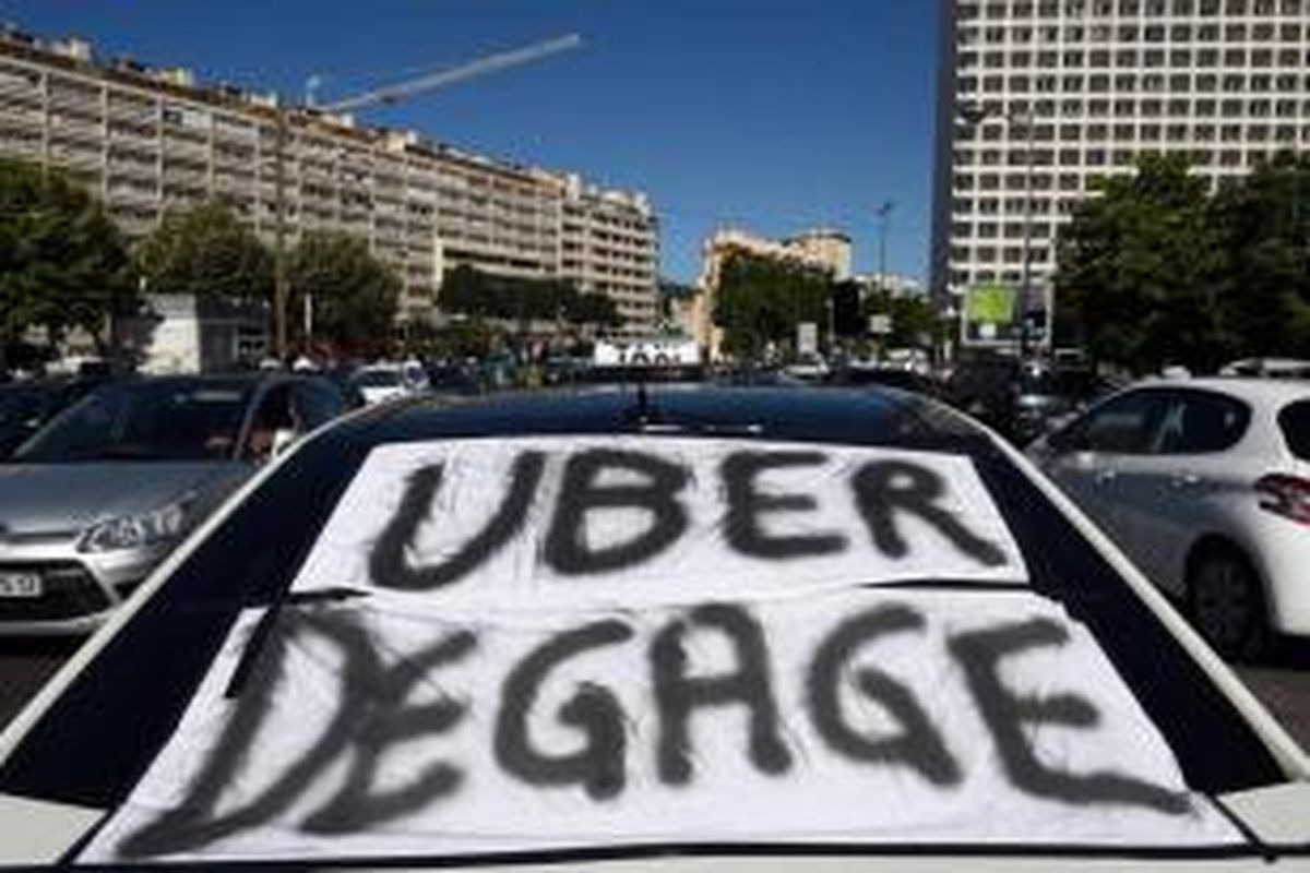 Sebuah taksi dengan banner tertulis 'Uber keluar' terlihat saat demonstrasi para sopir taksi memnentang keberadaan aplikasi layanan sewa mobil Uber di Marseille, 25 Juni 2015.