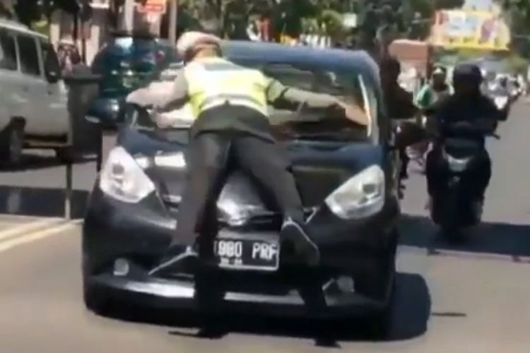 Petugas kepolisian mencoba memberhentikan pelanggar lalu lintas