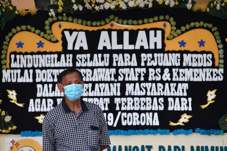 Warga berdiri di depan karangan bunga dukungan untuk tenaga medis dan staf Rumah Sakit Penyakit Infeksi (RSPI) Sulianti Saroso di Jakarta, Sabtu (21/3/2020). Puluhan kiriman karangan bunga dari masyarakat terpasang sejak Jumat (20/3) berisi doa untuk tenaga medis agar terus sehat selama menangani pasien terinfeksi COVID-19 di Indonesia.