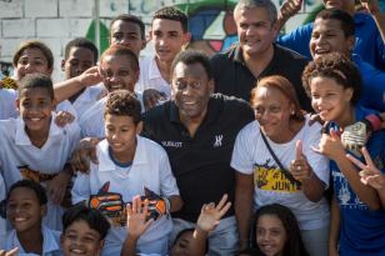 Legenda sepak bola Brasil, Pele (tengah), berfoto dengan anak-anak pada pembukaan lapangan sepak bola donasi perusahaan jam tangan Hublot, di Jacarezinho shantytown, Rio De Janeiro, 27 Juni 2014.
