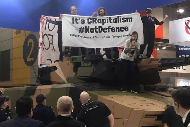 Sejumlah demonstran menaiki tank yang dipajang dalam expo persenjataan di Brisbane, hari Rabu (2/6/2021).