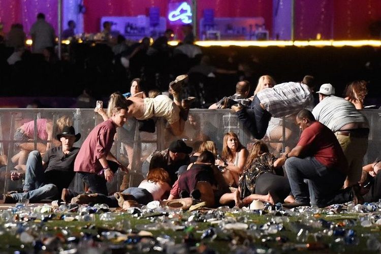 Orang-orang berlindung di festival musik country Route 91 Harvest setelah mendengar suara tembakan senjata di Las Vegas, Nevada, Minggu (1/10/2017). Seorang pria bersenjata melepaskan serentetan tembakan di festival musik tersebut hingga menyebabkan sedikitnya 50 orang tewas dan lebih dari 200 orang lain luka-luka. Polisi telah menembak satu orang tersangka. Investigasi sedang berlangsung.