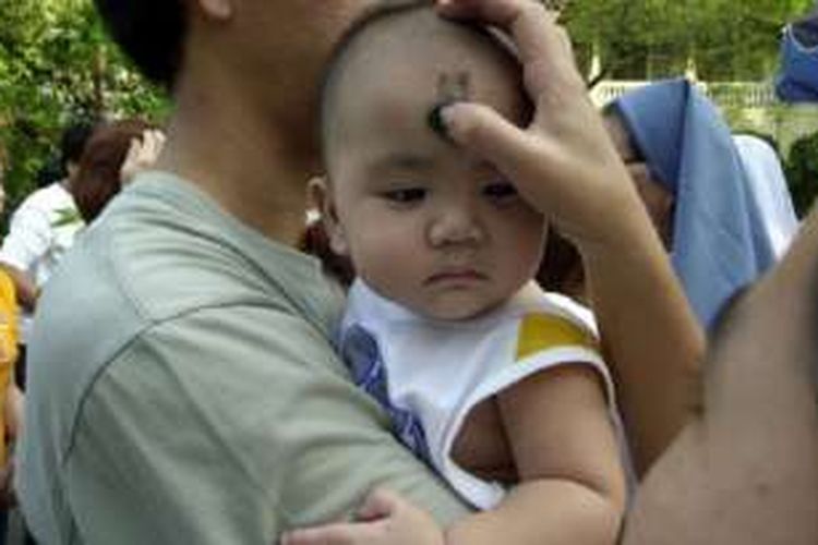Seorang biarawati menandai dahi seorang anak kecil di Manila, Filipina, pada hari Rabu Abu.

