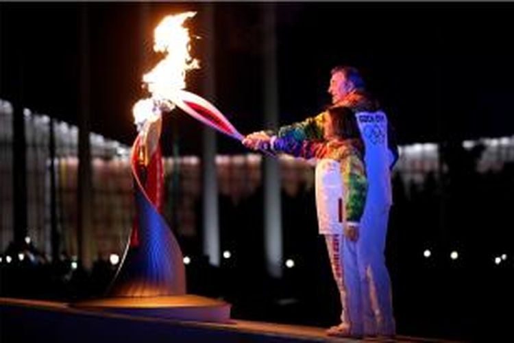 Pembawa obor olimpiade musim dingin Irina Rodnina (kiri) dan Vladislav Tretyak menyalakan api tanda pembukaan perlombaan internasional Jumat (7/2/2014).