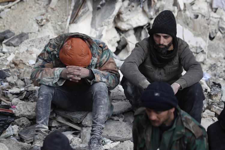 Korban gempa Suriah duduk di atas reruntuhan bangunan di Aleppo, Suriah, Selasa (7/2/2023). Gempa di Turki atau Turkiye dan Suriah bermagnitudo 7,8 pada Senin (6/2/2023), sejauh ini menewaskan lebih dari 5.000 orang.