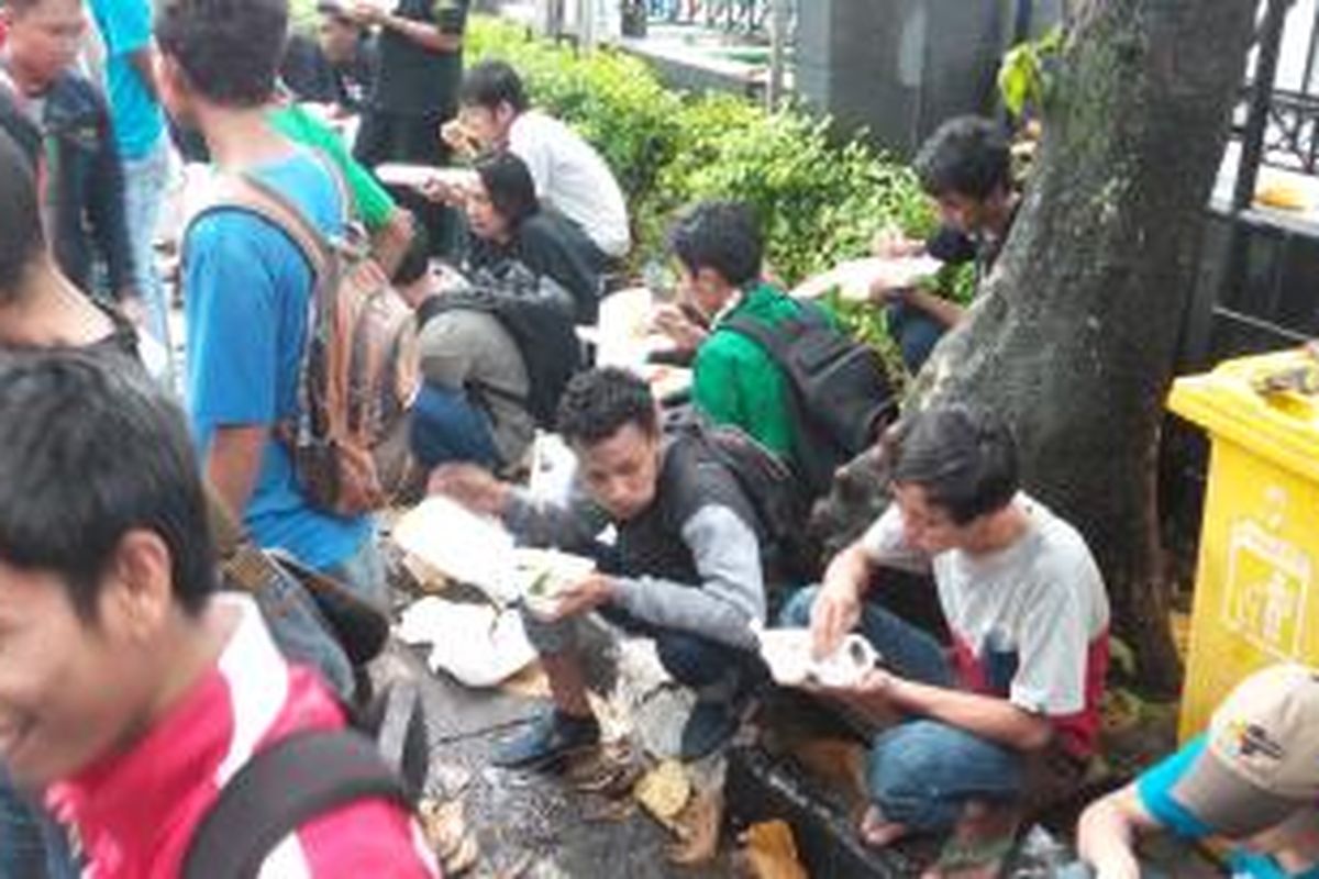 Sejumlah massa pendukung Komisaris Jenderal Budi Gunawan yang sedang menyantap nasi kotak yang dibagikan usai pembacaan putusan sidang pra peradilan, di halaman Pengadilan Negeri Jakarta Selatan, Senin (16/2/2015)