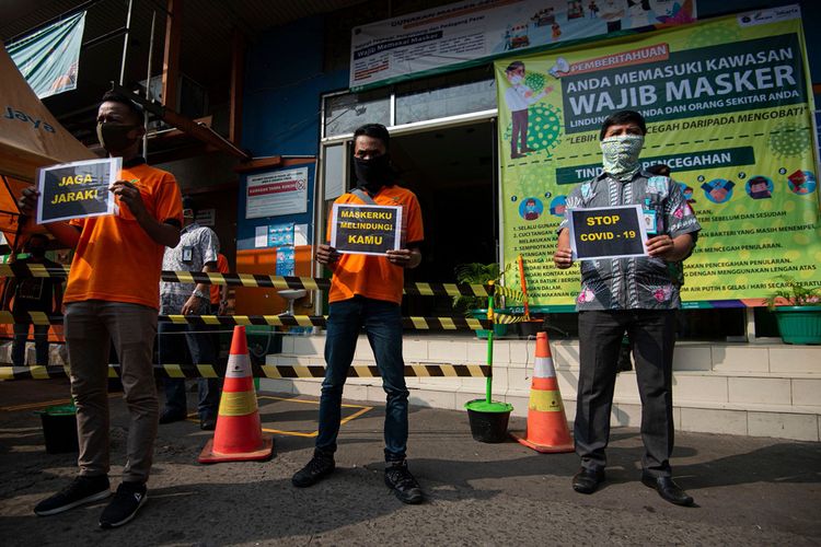 Petugas pengelola pasar melakukan sosialisasi pencegahan COVID-19 dengan membawa poster berisi pesan di Pasar Jatinegara, Jakarta, Kamis (11/6/2020). Upaya tersebut untuk meminimalisir kasus penularan atau penyebaran COVID-19 terjadi di pasar.