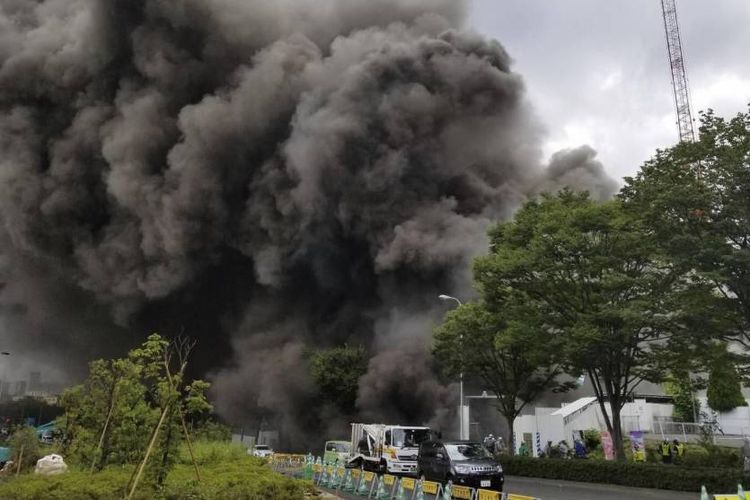 Asap membumbung dari lokasi konstruksi sebuah gedung berlantai tiga di Tama, Tokyo, Kamis (26/7/2018).