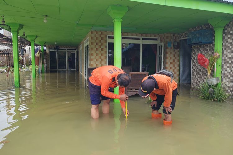 Ket. Foto: Petugas BPBD Sumenep mengukur ketinggian air di wilayah terdampak banjir