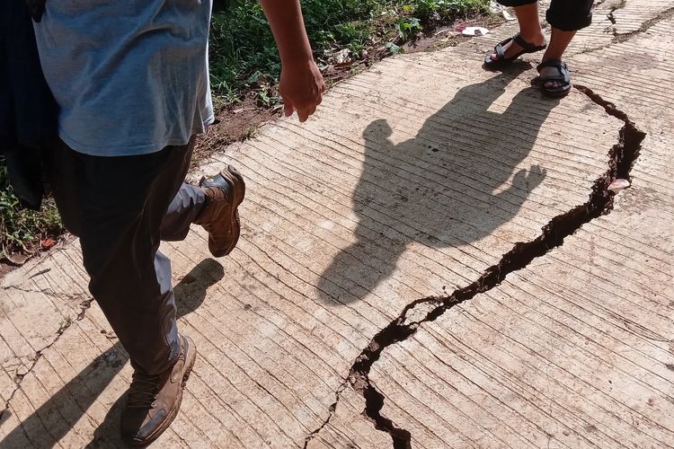 Sejumlah warga melintas di atas jalan lingkungan di Desa Jatisari, Kecamatan Bojongpicung. Kabupaten Cianjur, Jawa Barat, Sabtu (27/4/2024) yang kondisinya retak akibat tanah bergerak
