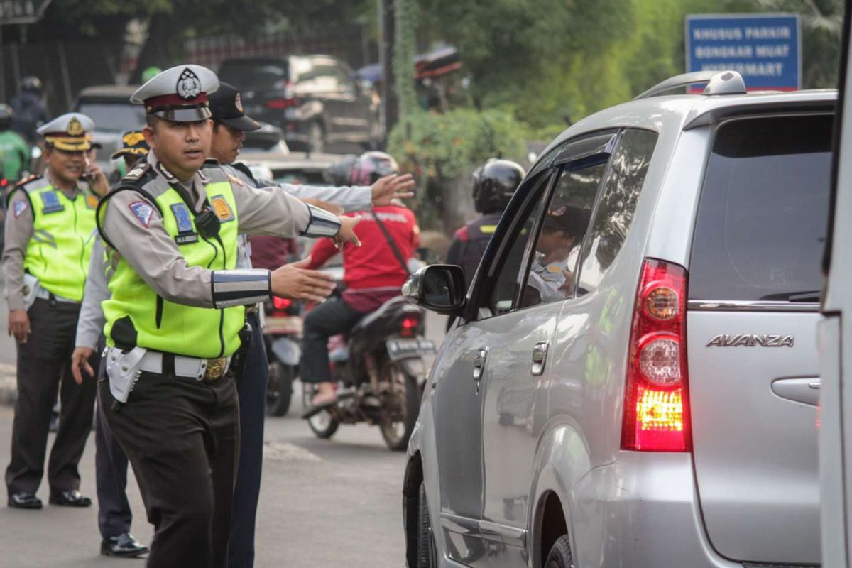Sejumlah petugas kepolisian memberi arahan kepada pengendara mobil pada uji coba ganjil genap di ruas Tol Jagorawi, Jakarta, Senin (16/4/2018). Uji coba yang dilakukan setiap hari Senin-Jumat kecuali hari libur nasional tersebut dimulai pukul 06.00 hingga 09.00 WIB diharapkan dapat mengurai kemacetan.