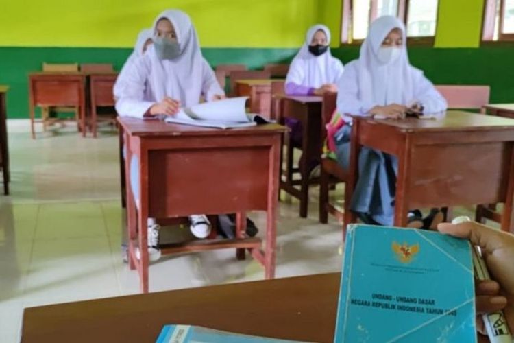 Seorang guru sedang mengajarkan ideologi Pancasila dengan siswanya