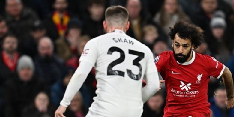 Pemain sayap Liverpool, Mohamed Salah (tengah), melepaskan umpan di antara penjagaan dua pemain Manchester United, Luke Shaw dan Alejandro Garnacho. Laga Liverpool vs Man United pada pekan ke-17 Liga Inggris 2023-2024 tersebut digelar di Stadion Anfield, Minggu (17/12/2023). (Foto oleh PAUL ELLIS/AFP)