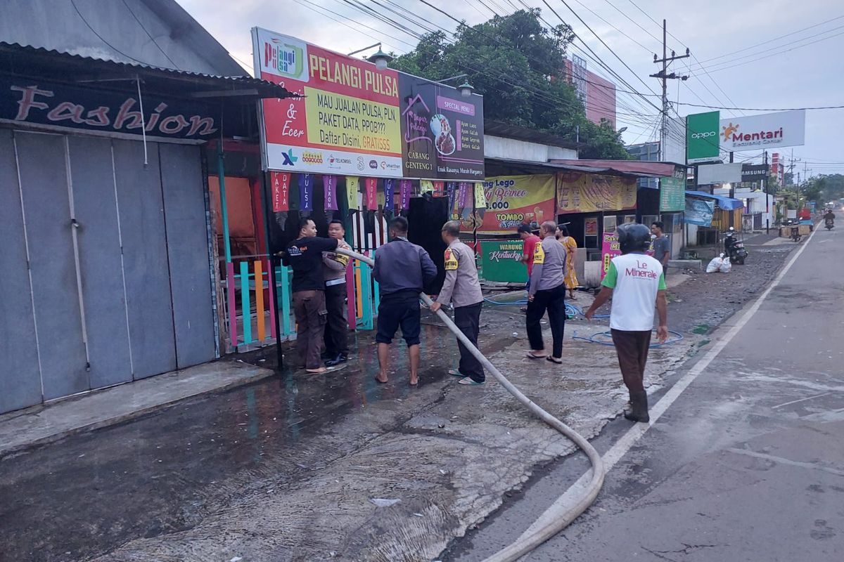 Petugas saat memadamkan api dalam kebekaran kios ponsel di Banyuwangi, Jumat (30/12/2022)